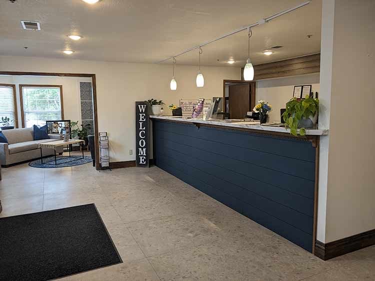 The front desk with navy shiplap paneling and a tall WELCOME sign