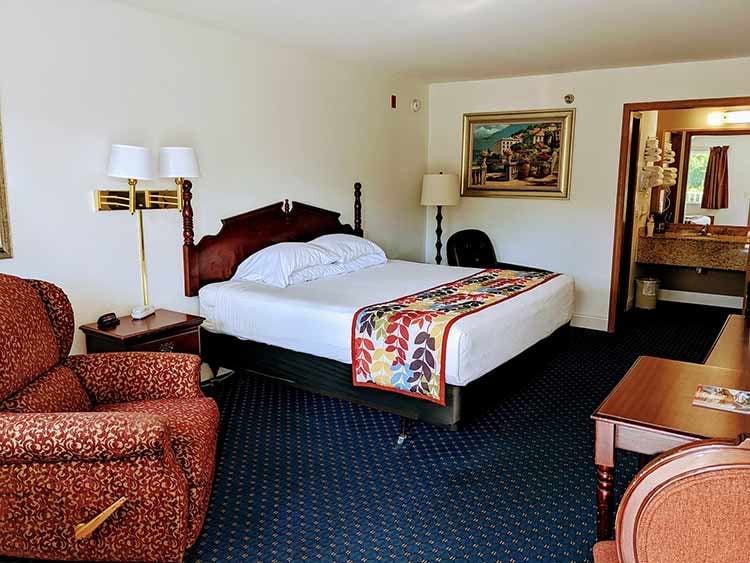 Single Queen room with a carved headboard and a red armchair