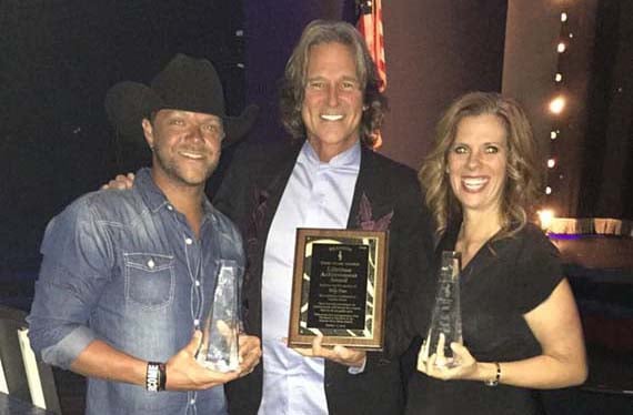 Amy Dutton holding her fiddle player of the year award with two other award winners