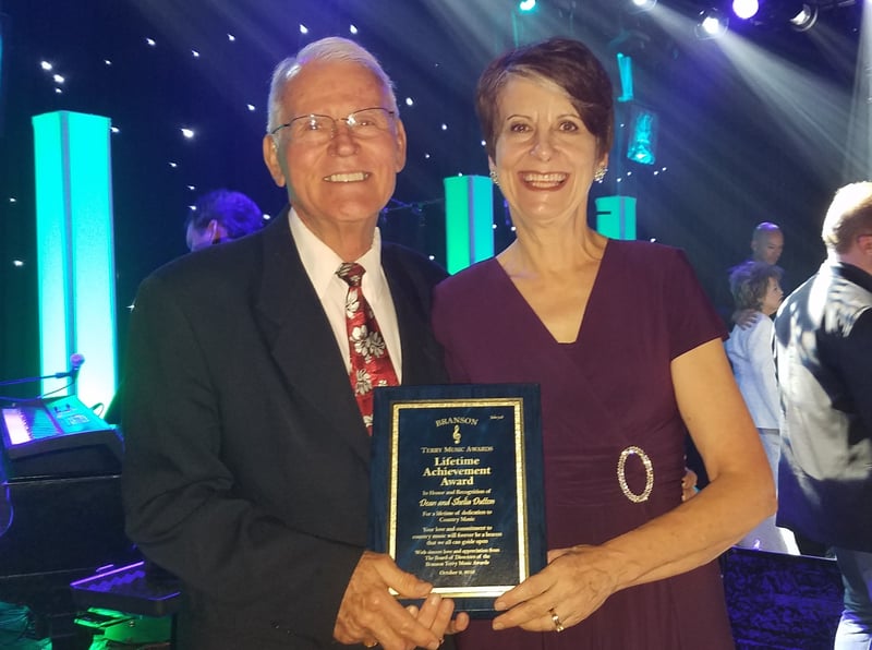 Dean and Sheila Dutton holding their lifetime achievement award plaque on stage