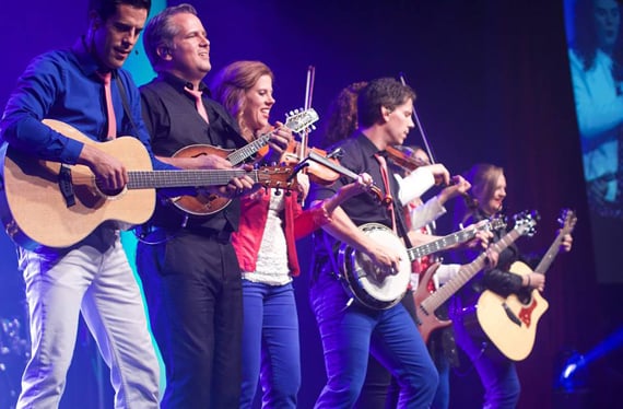 The Duttons playing guitars, banjo and fiddles on stage