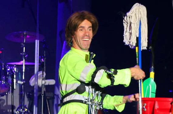 A Dutton performer in a neon safety vest holding a mop during a comedy bit