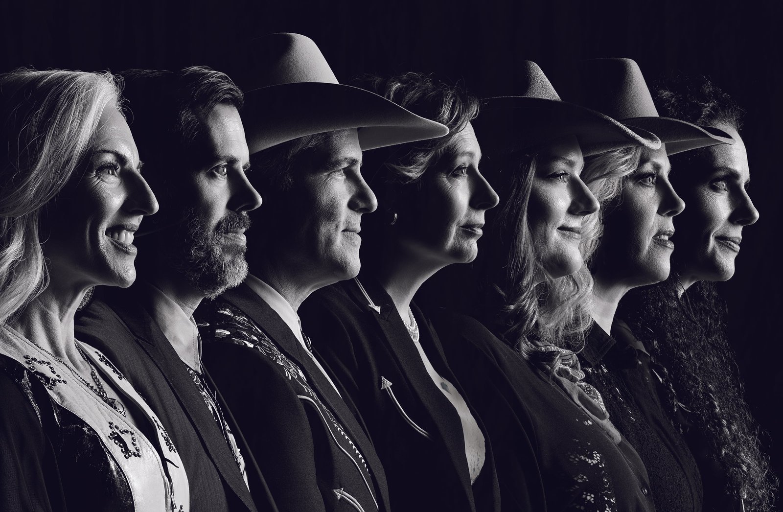 Black-and-white profile portrait of seven Dutton family members in a row, several in cowboy hats, all facing right