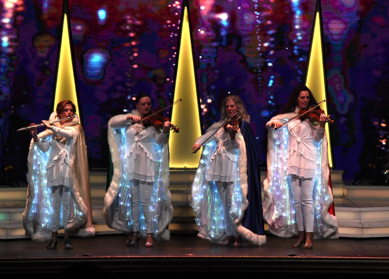 Dutton family members in glowing white angel costumes playing violins on stage