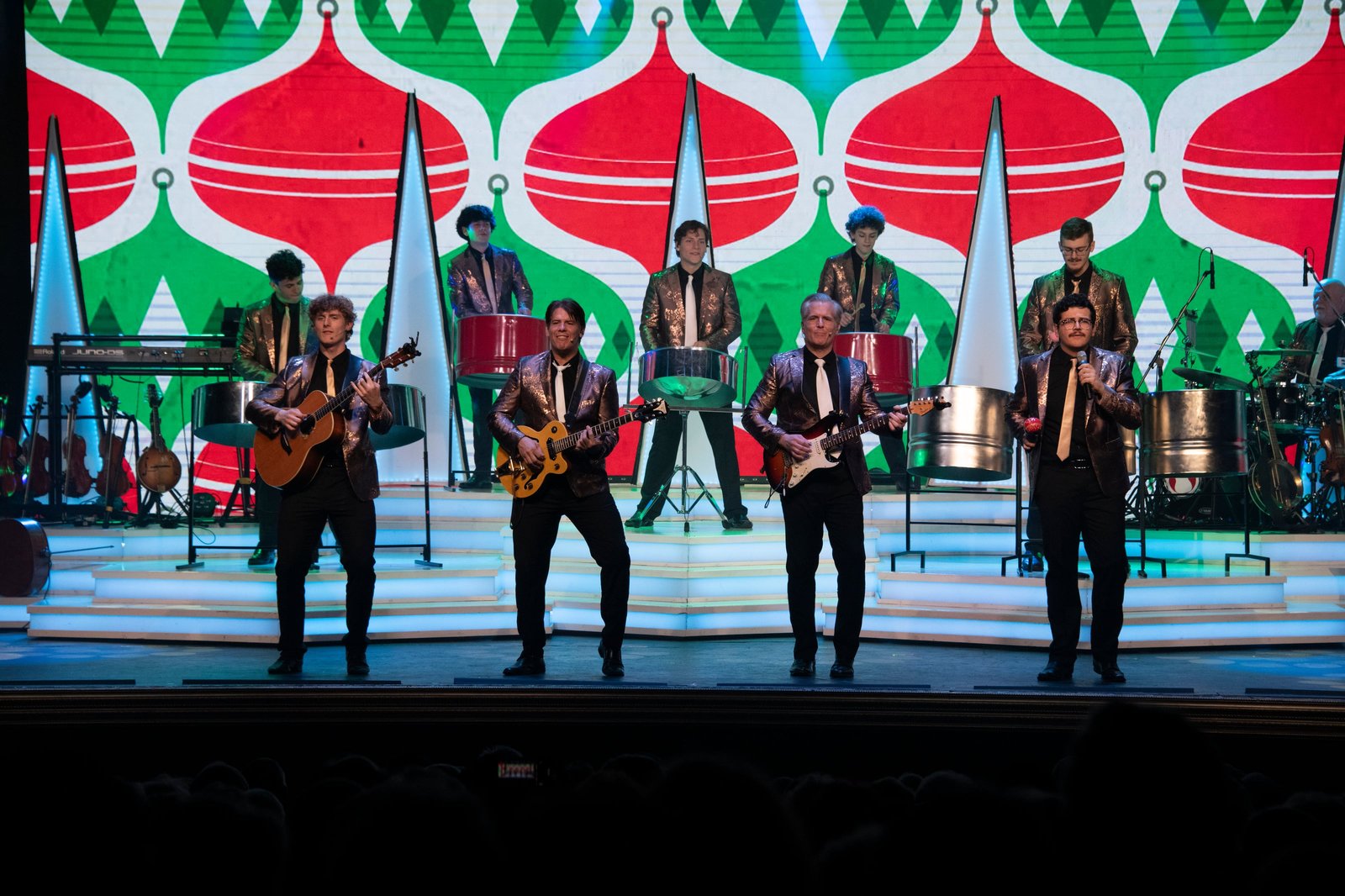 The full Dutton band performing in front of a red and green ornament backdrop