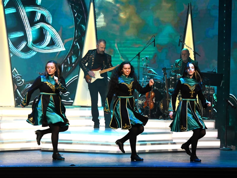 Irish dancers and fiddlers performing in front of a Celtic knot backdrop