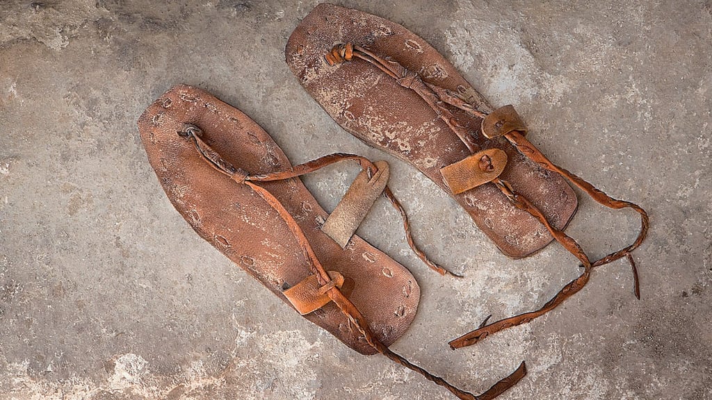 A worn pair of leather sandals on stone