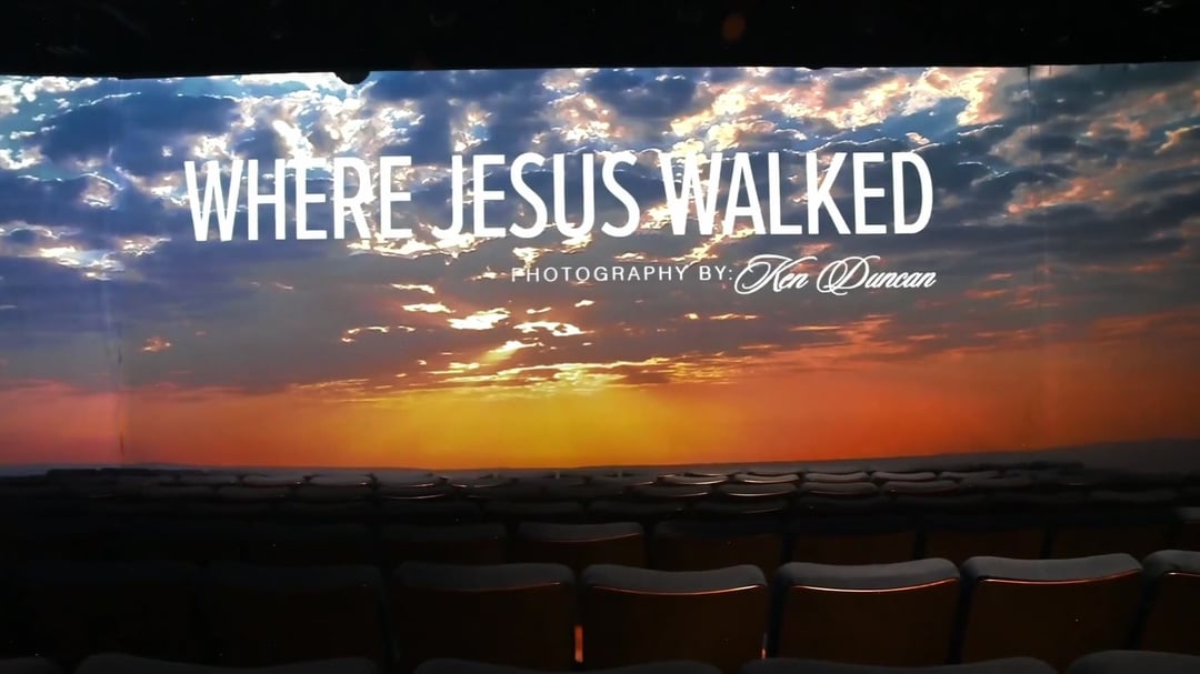 The Where Jesus Walked title on the wraparound screens above rows of theater seats