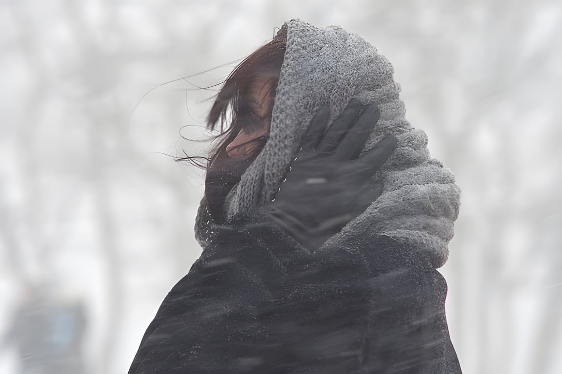 Девушка кутается в шаль при сильном ветре и метели. Шторм. Фото Сергея Серебро