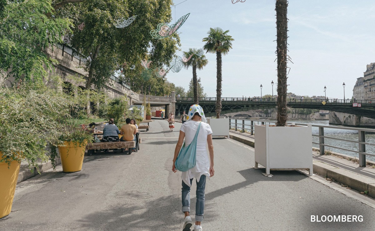 A pedestrian in Paris wears a head covering to shield from the sun at a Paris Plage temporary beach, Aug. 14, 2023.
