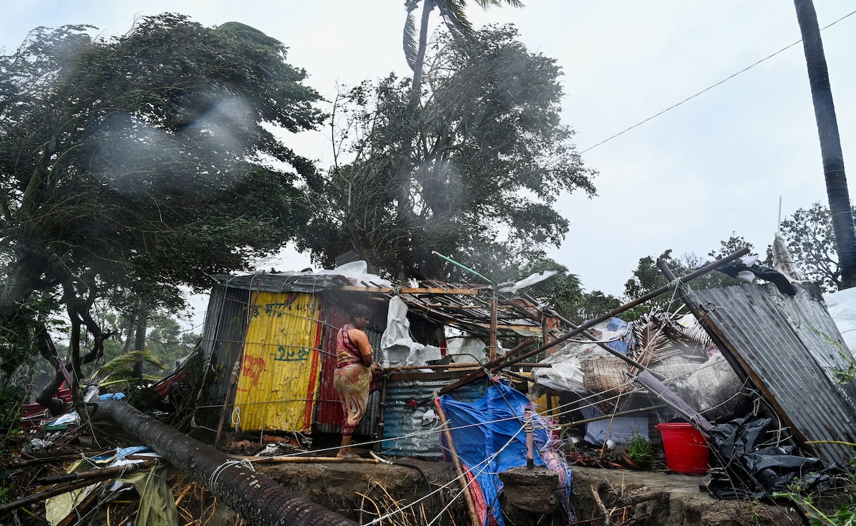 A woman stands next to her damaged house near a beach in Kuakata.