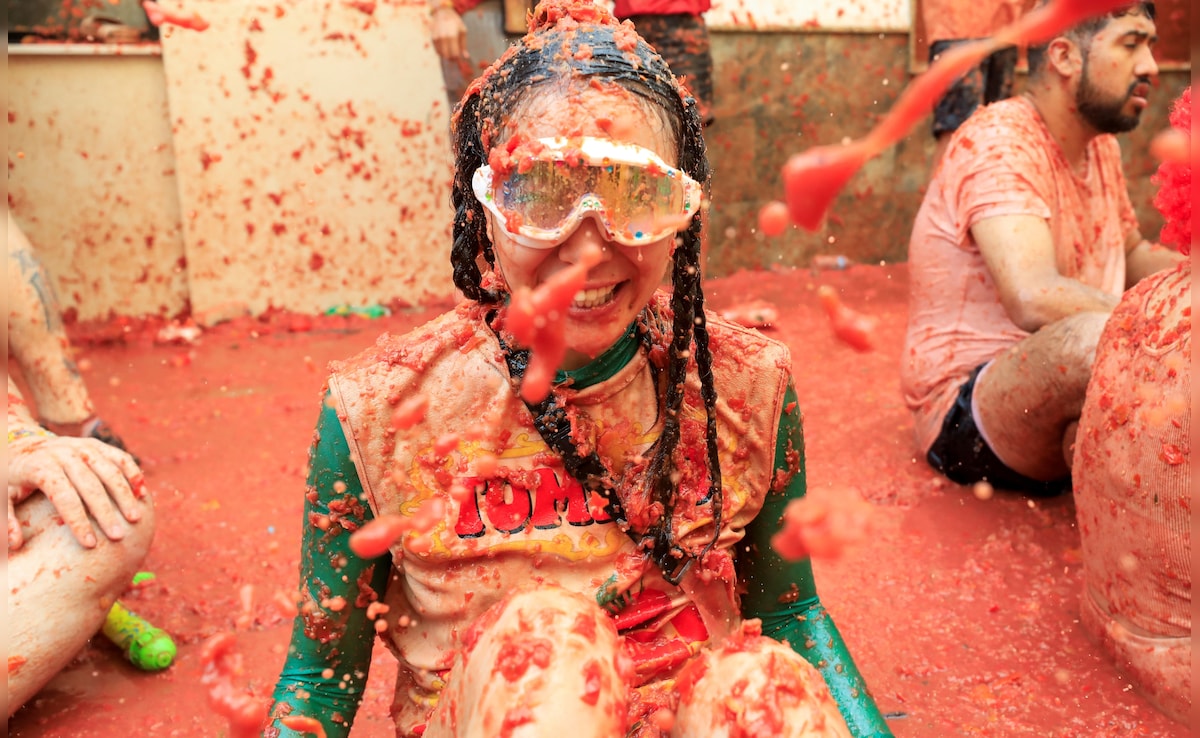 A participant covered in tomato pulp looks on, as people attend the annual food fight festival La Tomatina in Bunol, near Valencia, Spain