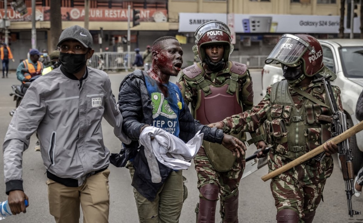 Kenya Police officers detain an injured man during an anti-government demonstration