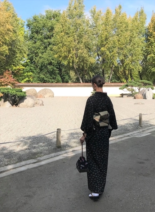 Anita Henry en kimono de type Komon et portant à la main un kinchaku 巾着 "sac kimono" sac à cordon traditionnel japonais, utilisé comme sac à main. La base de ce sac est tissé en rotin, la partie principal est en soie, ici, avec des motifs de flèches: yabane 矢羽根 Anita Henry en kimono de type Komon et portant à la main un kinchaku 巾着 "sac kimono" sac à cordon traditionnel japonais, utilisé comme sac à main. La base de ce sac est tissé en rotin, la partie principal est en soie, ici, avec des motifs de flèches: yabane 矢羽根