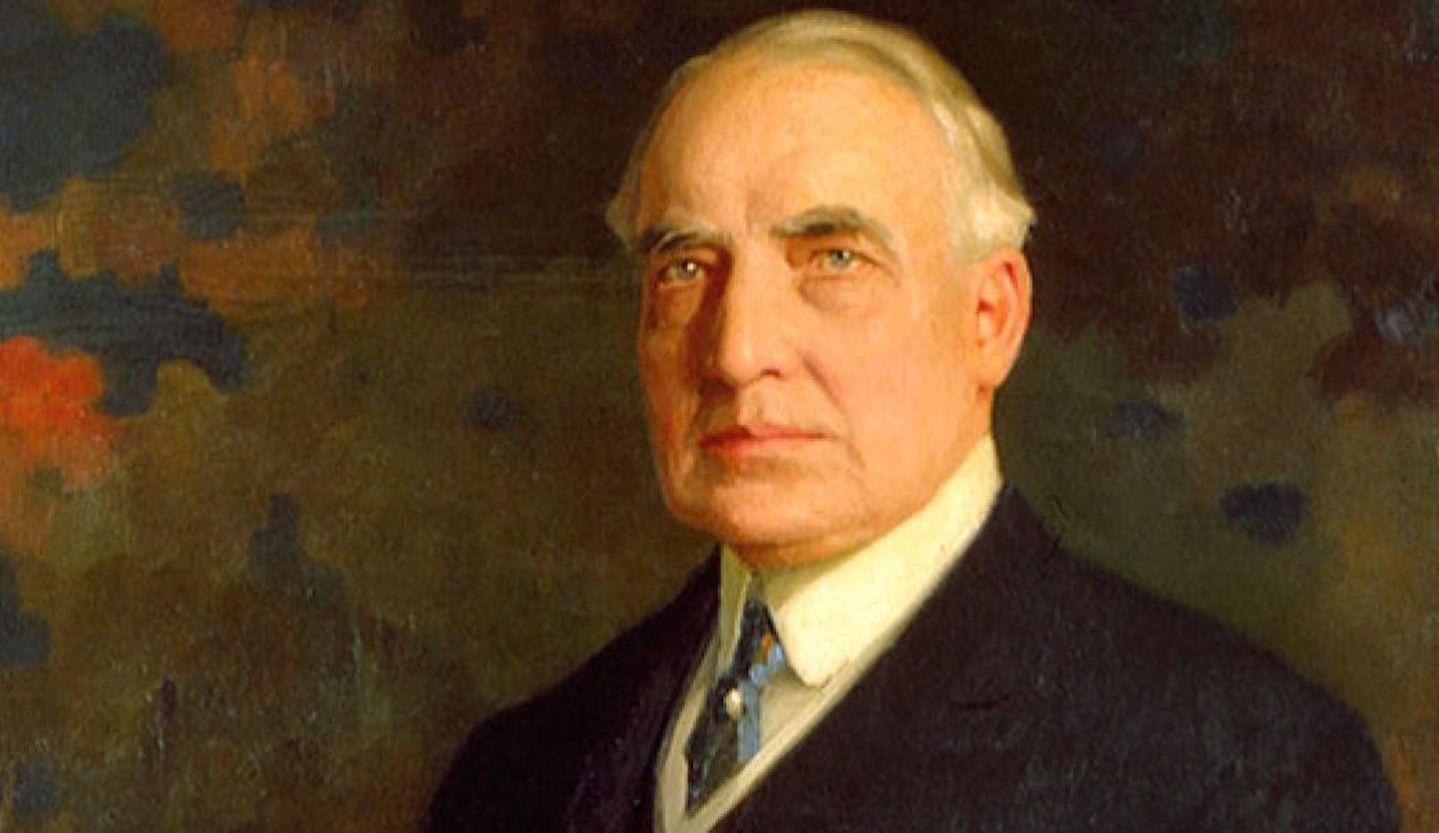 Portrait de Warren G. Harding, 29e président des États-Unis, vêtu d'un costume sombre et d'une cravate claire. L'arrière-plan est flou et de teintes foncées.
