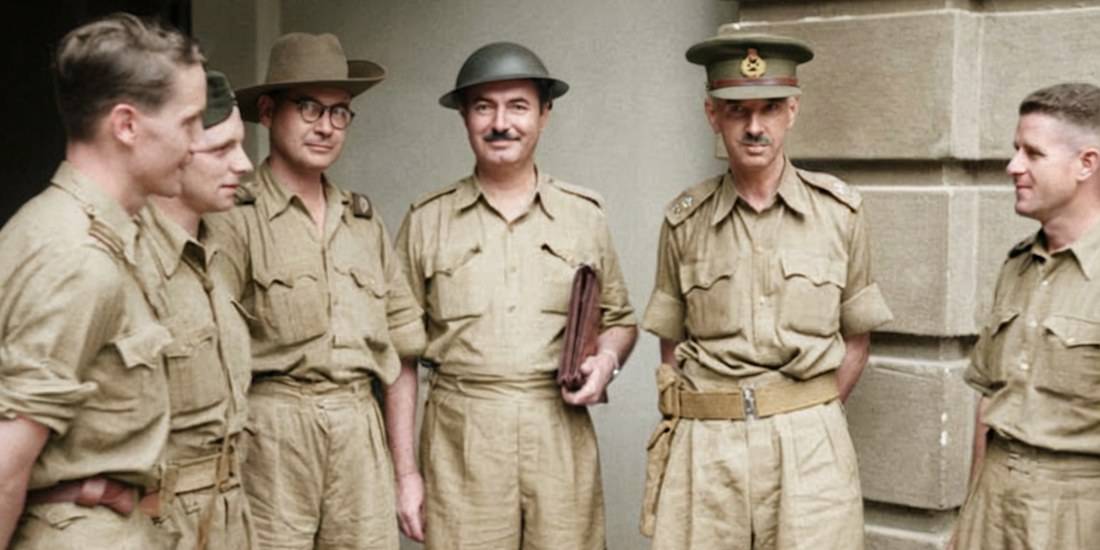 Portrait historique colorisé du Lieutenant-Général Arthur Percival en uniforme de l'armée britannique discutant avec des correspondants de guerre à Singapour en janvier 1942, peu avant la chute de la ville pendant la Seconde Guerre mondiale.