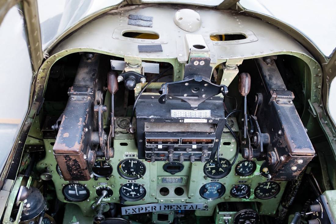 Vue rapprochée de l'intérieur du cockpit d'un avion de chasse japonais Mitsubishi A6M3 Zero, montrant le tableau de bord avec ses cadrans analogiques, les commandes de vol et les mitrailleuses de capot.