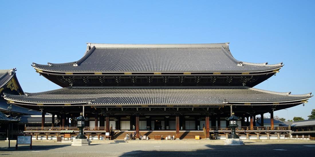 Temple bouddhiste Higashi Hongan-ji à Kyoto avec son architecture traditionnelle en bois et son toit massif sous un ciel bleu clair.