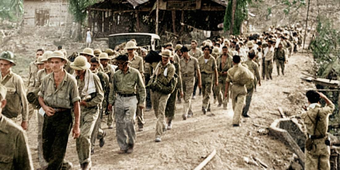 Soldats américains et philippins prisonniers de guerre marchant sous la garde de soldats japonais lors de la marche de la mort de Bataan aux Philippines en 1942.