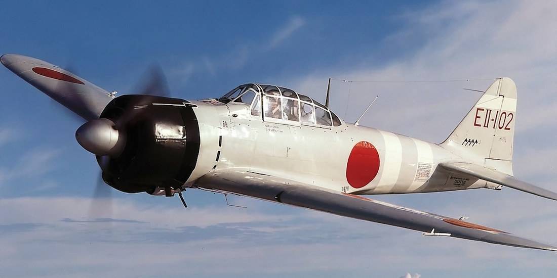 Chasseur japonais Mitsubishi A6M Zero en plein vol sur fond de ciel bleu avec les insignes du soleil levant.