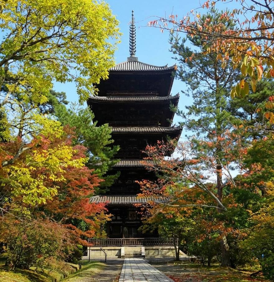 Pagode à cinq étages du temple Ninna-ji à Kyoto entourée d'arbres aux couleurs d'automne sous un ciel bleu clair.