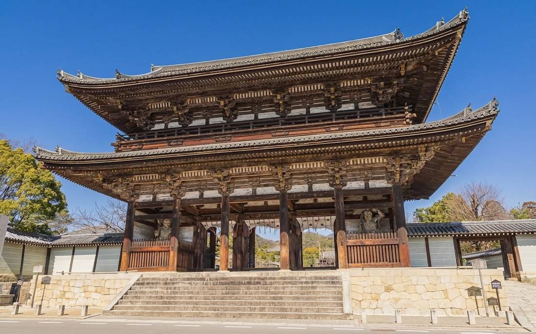 Porte Niomon monumentale en bois du temple Ninna-ji à Kyoto, Japon, avec ses statues de gardiens Nio sous un ciel bleu clair.