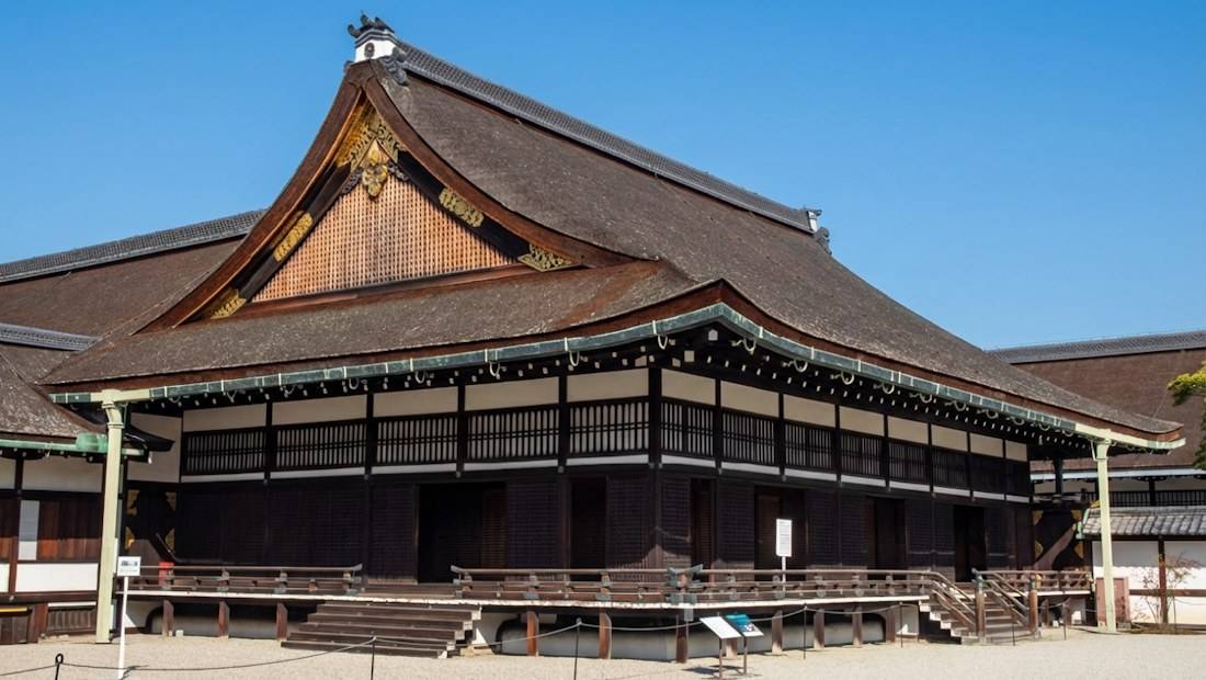 Bâtiment historique Ogakumonjo au Palais Impérial de Kyoto avec son toit en écorce de cyprès et son architecture traditionnelle japonaise sous un ciel bleu.