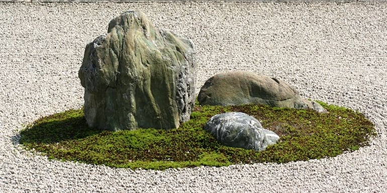 Gros plan sur une composition de rochers entourés de mousse verte sur un lit de gravier blanc ratissé dans le jardin zen du temple Ryoan-ji à Kyoto, Japon.