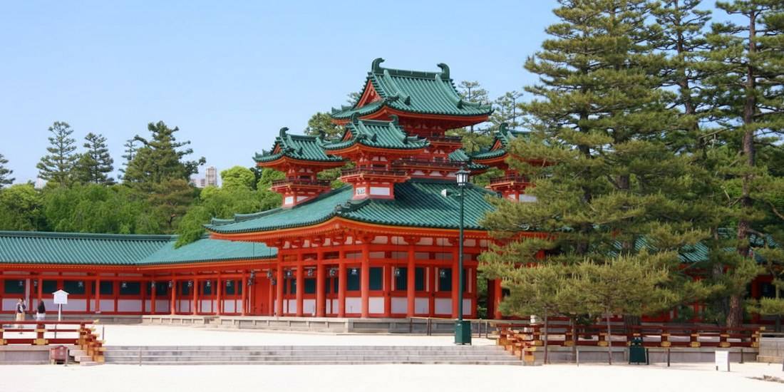 Vue extérieure de la tour Soryu-ro du sanctuaire Heian-jingu à Kyoto, Japon, montrant l'architecture traditionnelle avec des toits de tuiles vertes et des piliers vermillon sous un ciel bleu.