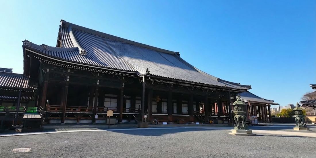Vue panoramique de l'Amida-do, le hall principal du temple Nishi Hongan-ji à Kyoto, Japon, montrant l'architecture bouddhiste traditionnelle en bois sous un ciel bleu clair.