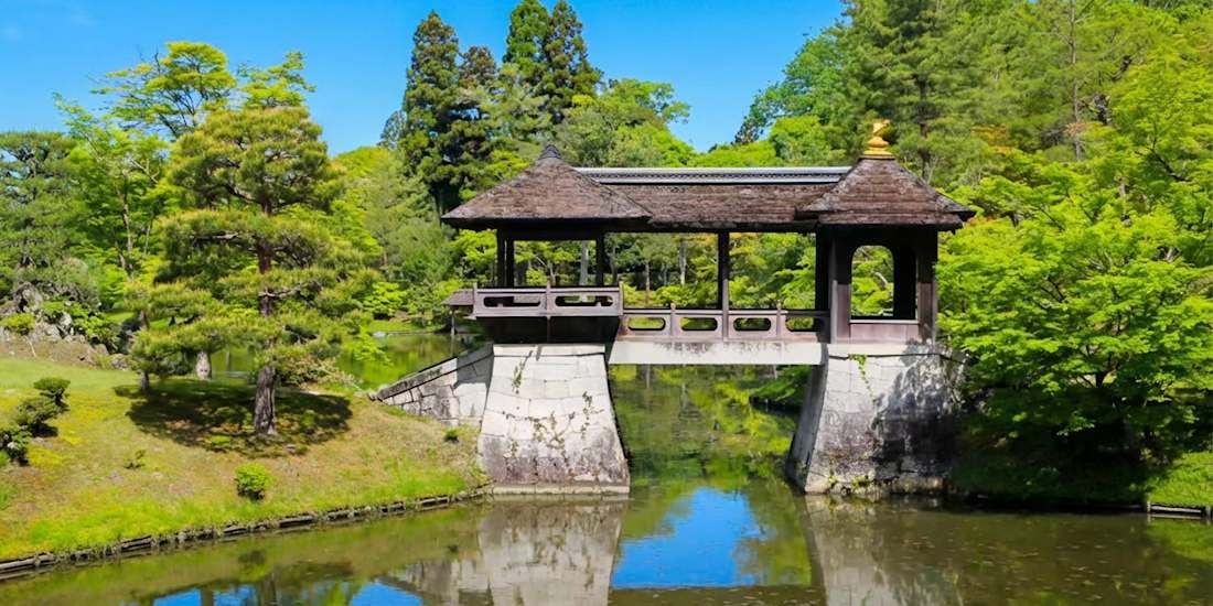 Pont Chitose-bashi au jardin de la villa impériale Shugaku-in à Kyoto, entouré de verdure et reflété dans l’eau