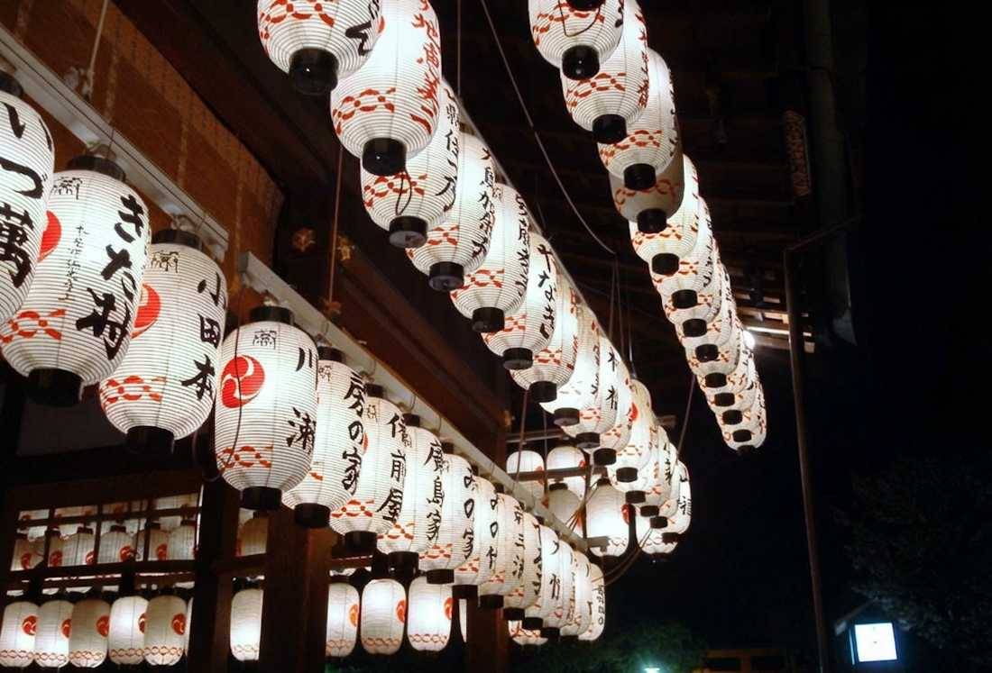 Lanternes japonaises traditionnelles chochin éclairées de nuit au sanctuaire Yasaka-jinja à Kyoto, Japon, avec des inscriptions en calligraphie noire.
