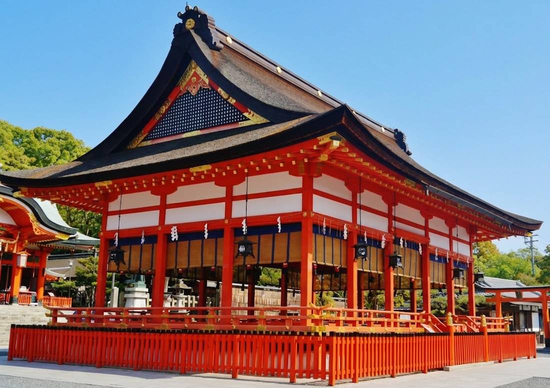 Pavillon Ge-heiden du sanctuaire Fushimi Inari Taisha à Kyoto, architecture traditionnelle japonaise en bois rouge vermillon sous un ciel bleu clair.