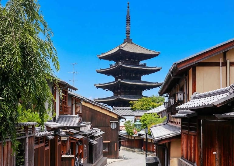 Vue de la pagode Yasaka-no-to dominant les rues traditionnelles du quartier de Gion à Kyoto, Japon, sous un ciel bleu clair.