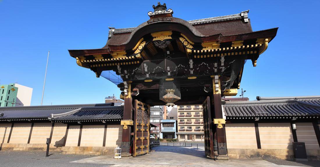 Porte Goeido-mon richement décorée du temple Nishi Hongan-ji à Kyoto, Japon, sous un ciel bleu clair.