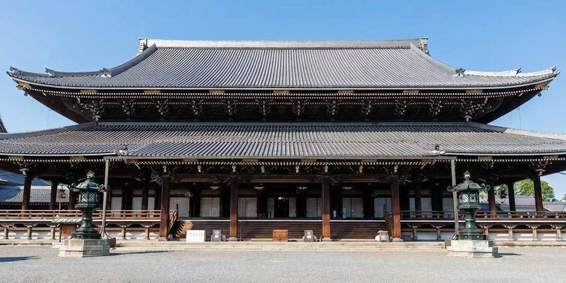 Temple bouddhiste Higashi Hongan-ji à Kyoto au Japon, vue de face de l'architecture traditionnelle en bois sous un ciel bleu clair.