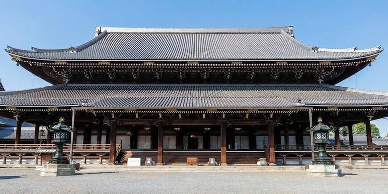 Temple bouddhiste Higashi Hongan-ji à Kyoto au Japon, vue de face de l'architecture traditionnelle en bois sous un ciel bleu clair.