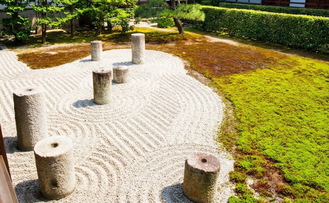 Jardin sec japonais du temple Tofuku-ji à Kyoto avec sept piliers en pierre cylindriques disposés comme la constellation de la Grande Ourse sur du gravier blanc ratissé et de la mousse verte.