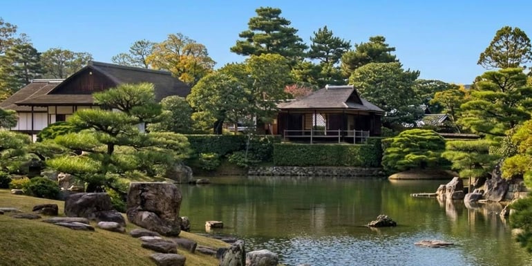 Vue panoramique du jardin japonais traditionnel et des pavillons en bois de la Villa impériale de Katsura à Kyoto, avec un étang paisible et des pins sculptés sous un ciel bleu.