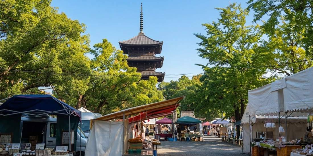 Marché aux puces Kobo-san avec étals de rue et vue sur la pagode en bois du temple To-ji sous un ciel bleu à Kyoto, Japon.