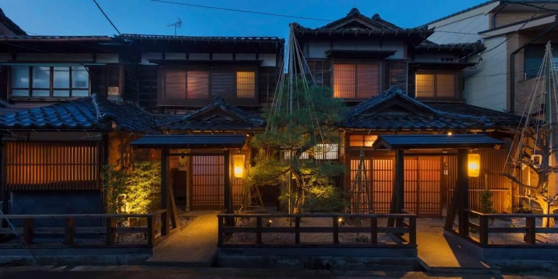 Machiya traditionnelles éclairées de nuit dans le quartier de Ponto-cho à Kyoto, Japon, avec lanternes dorées et architecture en bois.
