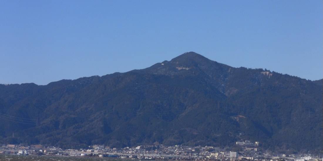 Vue panoramique du mont Hiei dominant la ville depuis les rives du lac Biwa au Japon sous un ciel bleu clair.