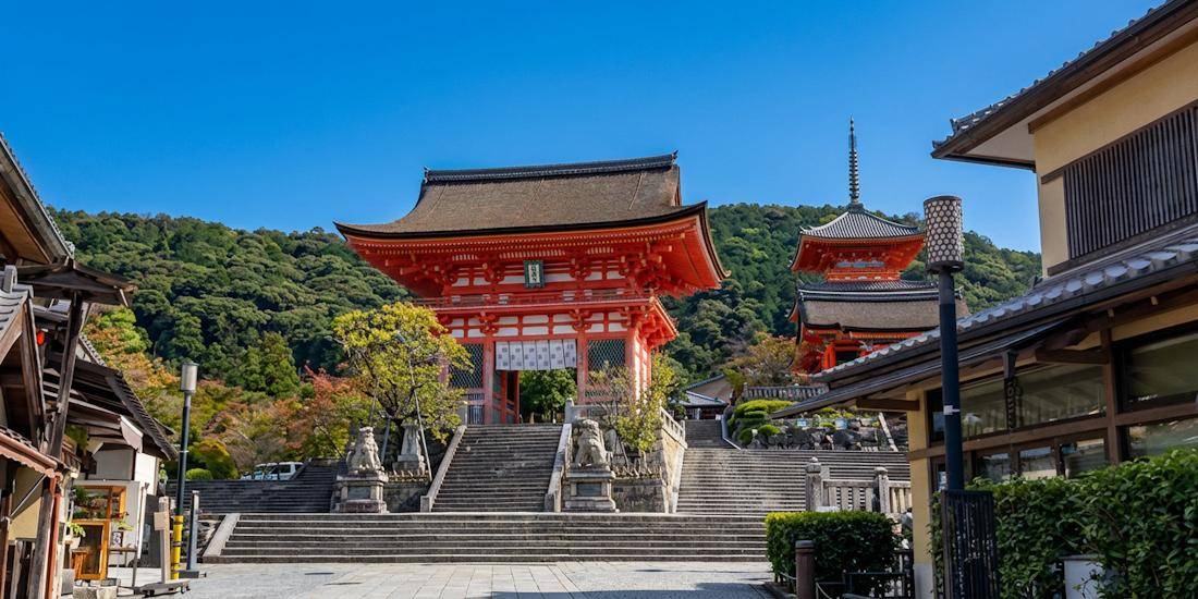 Porte Niomon rouge vif et pagode à trois étages du temple Kiyomizu-dera sous un ciel bleu à Kyoto, Japon.