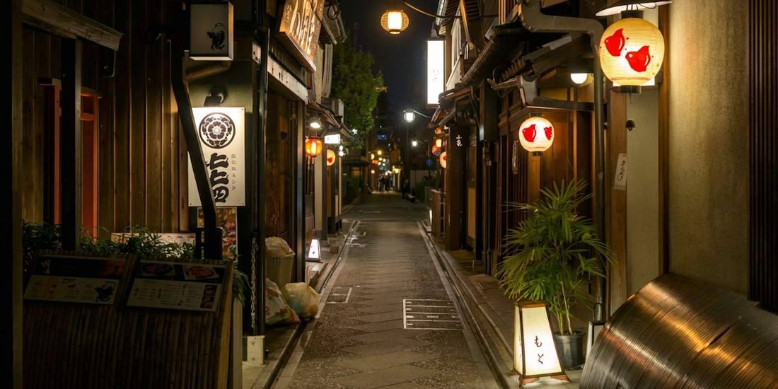 Ruelle étroite de Ponto-chō à Kyoto la nuit avec des lanternes traditionnelles éclairées devant des restaurants en bois.