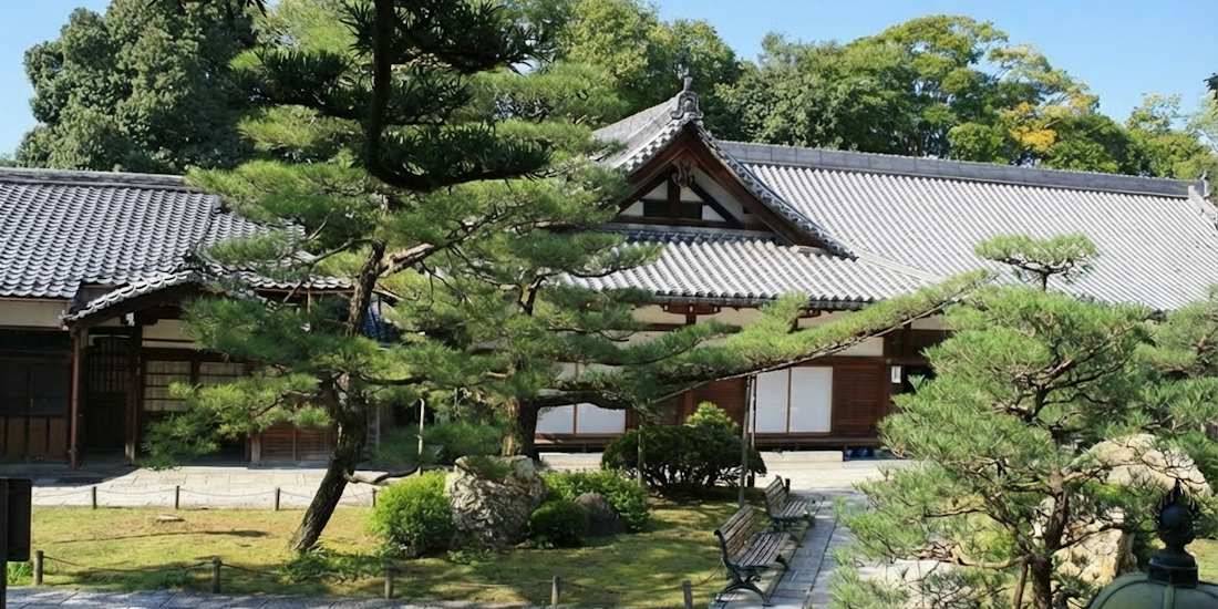 Mausolée Otani au temple bouddhiste Higashi Hongan-ji à Kyoto avec architecture traditionnelle japonaise, pins sculptés et jardin zen sous un ciel bleu.