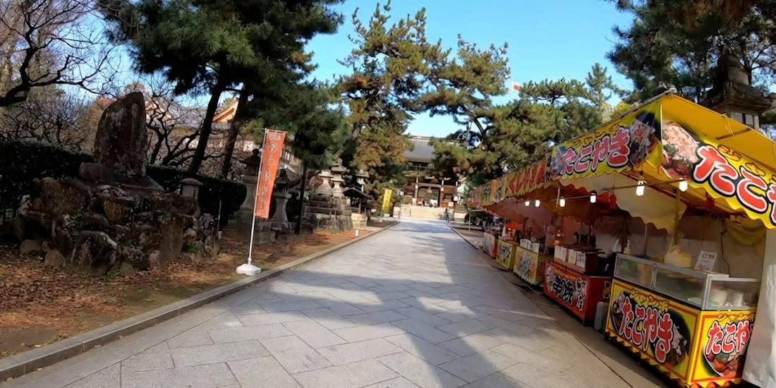 Marché Tenjin-san avec stands de nourriture de rue (takoyaki) et allée pavée menant au sanctuaire Kitano Tenmangu à Kyoto, Japon.