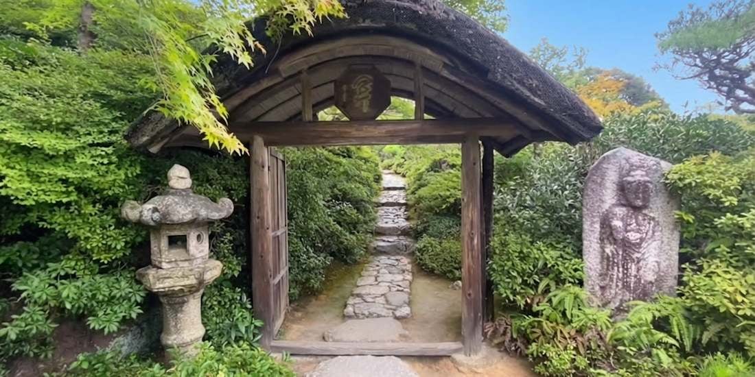 Porte traditionnelle chumon du jardin Okochi Sanso à Kyoto avec allée de pierres et végétation japonaise