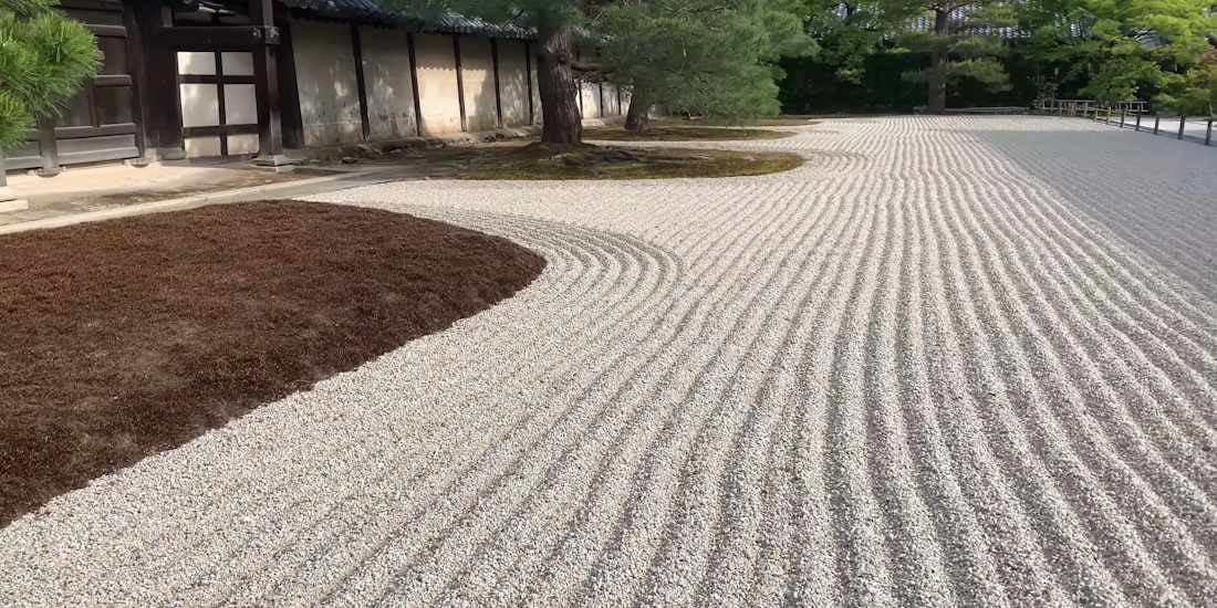 Jardin sec japonais Karesansui avec gravier blanc soigneusement ratissé en ondulations, mousses sombres et pins au temple Tenryū-ji à Kyoto, Japon.