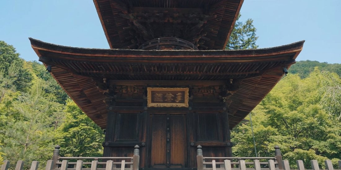 Vue en contre-plongée sous la pagode du temple Jōjakkō-ji à Kyoto, entourée de verdure