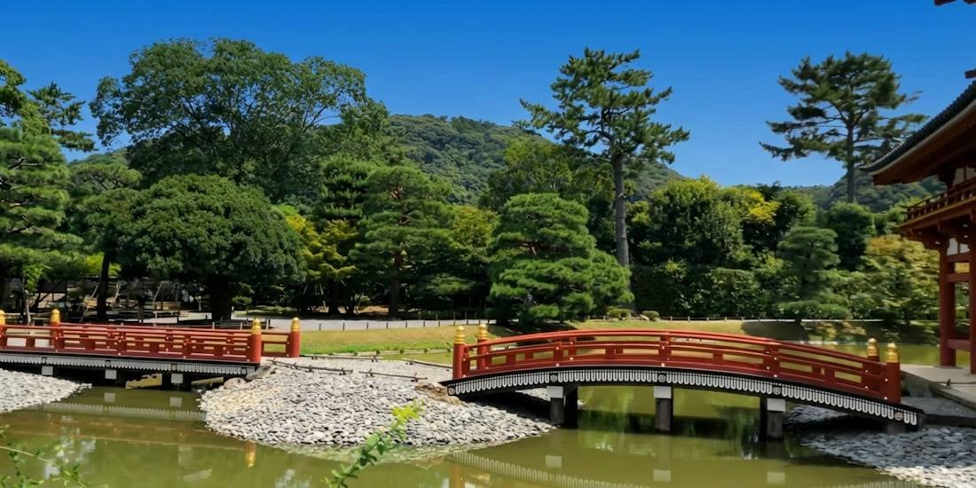Ponts rouges menant au pavillon du Phénix au temple Byodo-in à Kyoto entourés de nature verdoyante